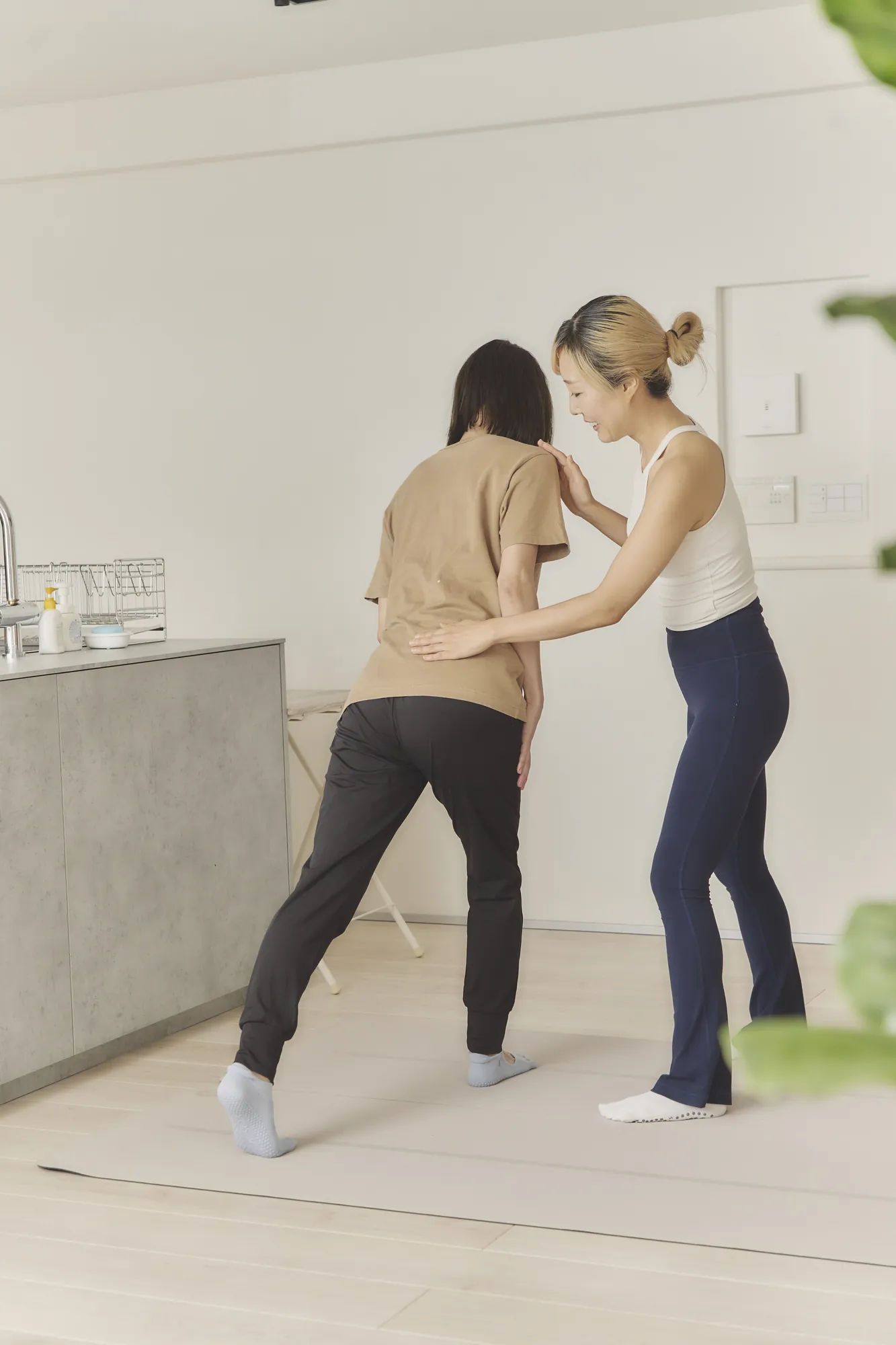 脚を前に出したお客様の肩と腰に手を添えるトレーナー