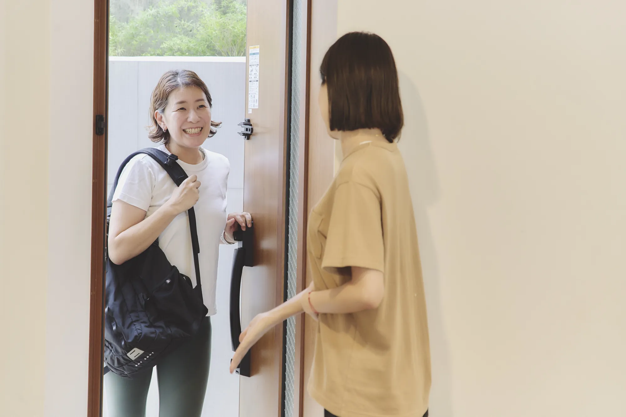 リュックを背負って玄関に着いたトレーナーを、ドアを開けて迎えるお客様