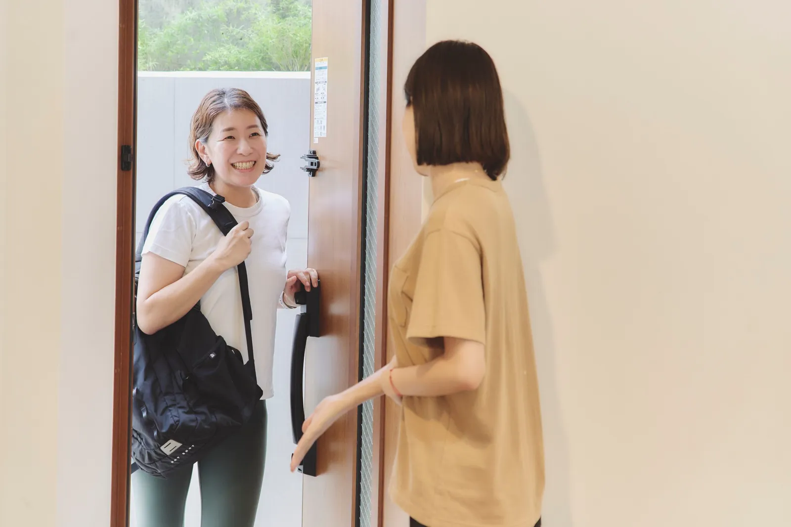 リュックを背負って玄関に着いたトレーナーと、ドアを開けて迎えるお客様