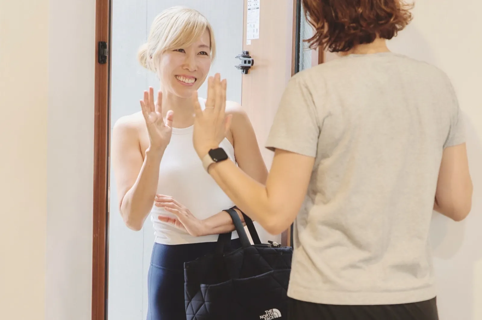 玄関先で手を振り合う、到着したトレーナーとお客様